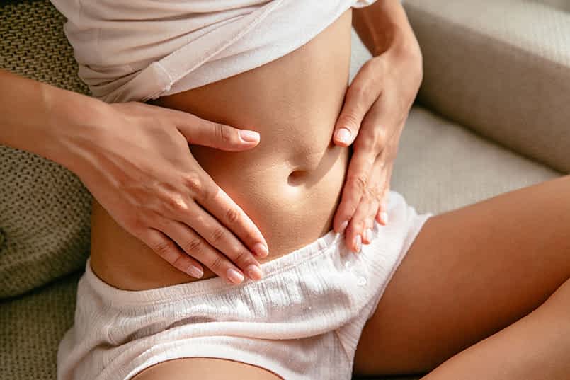 Close-up of a woman gently holding her stomach, promoting wellness and relaxation at a Colonic Spa in Chandler, AZ