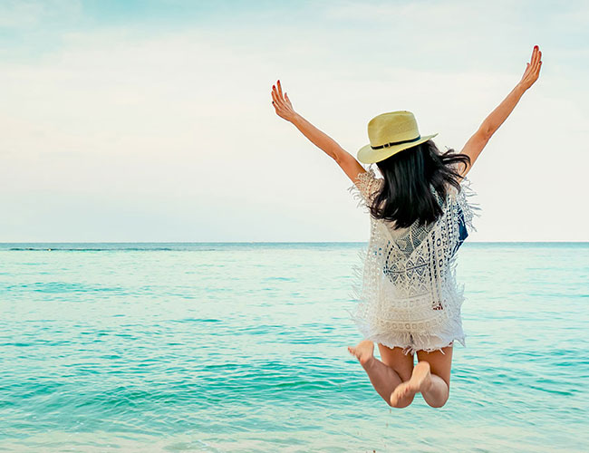 Person joyfully jumping on a serene beach, symbolizing the wellness and vitality achieved through the benefits of PEMF therapy