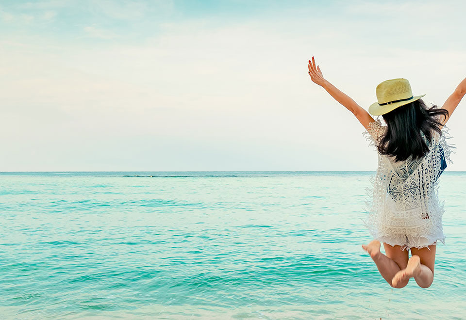 Person joyfully jumping on a serene beach, symbolizing the wellness and vitality achieved through the benefits of PEMF therapy