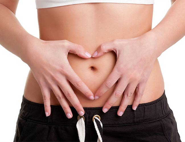 Close-up of a person’s stomach with hands forming a heart shape, symbolizing gut health and wellness at Colonic Spa Mesa AZ.