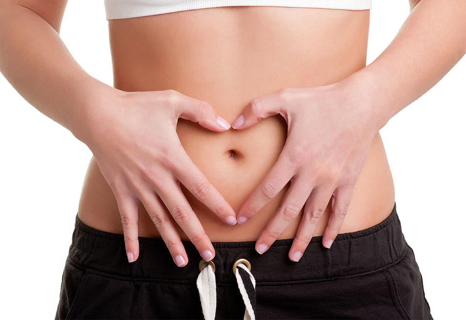 Close-up of a person’s stomach with hands forming a heart shape, symbolizing gut health and wellness at Colonic Spa Mesa AZ.