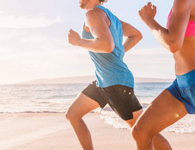 Couple running on the beach, showing active lifestyle and maintenance between colon hydrotherapy sessions.