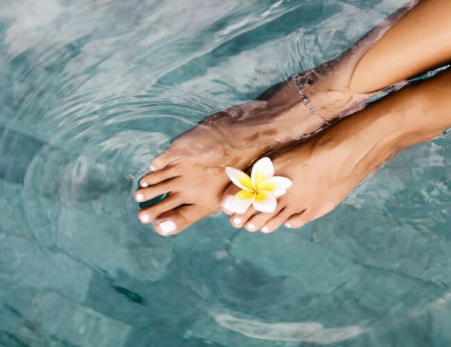 Feet in warm water during an aqua-ionic detox foot spa session, often added to colonics as a relaxing wellness routine at Amber Colonics
