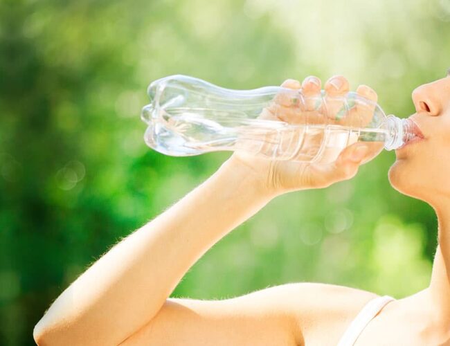 Woman drinking water outdoors, representing hydration before and after a first colon hydrotherapy session in Tempe