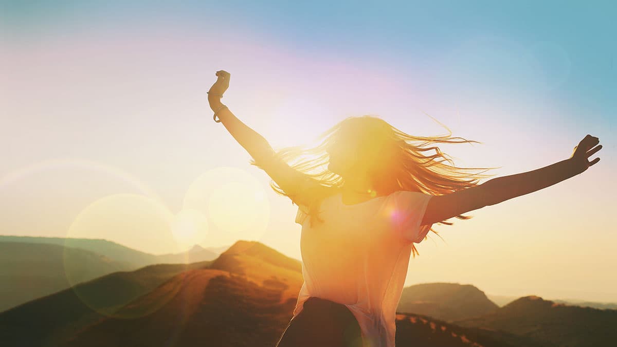 Woman standing with arms open at sunrise, representing the sense of relief and wellness many Phoenix-area clients look for when planning a colon hydrotherapy visit in Tempe