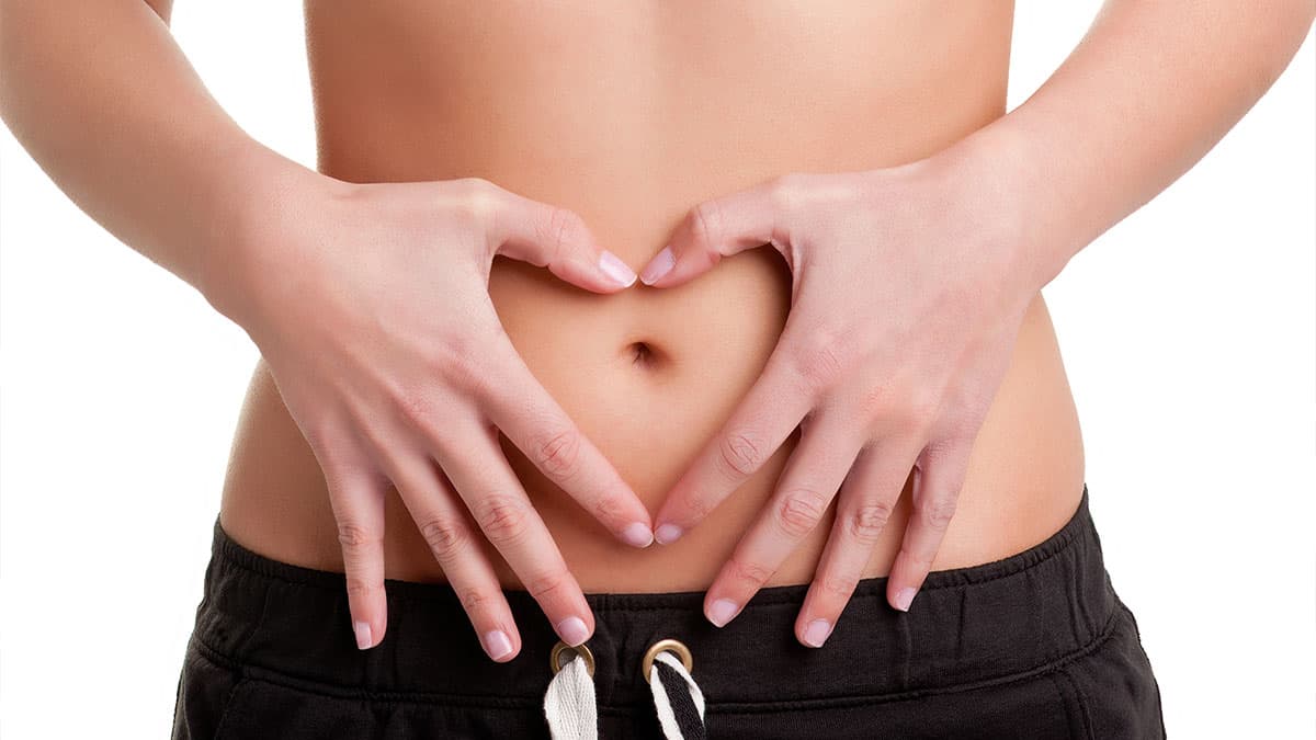 Woman forming a heart shape over her abdomen, representing digestive wellness and colon hydrotherapy in Tempe.