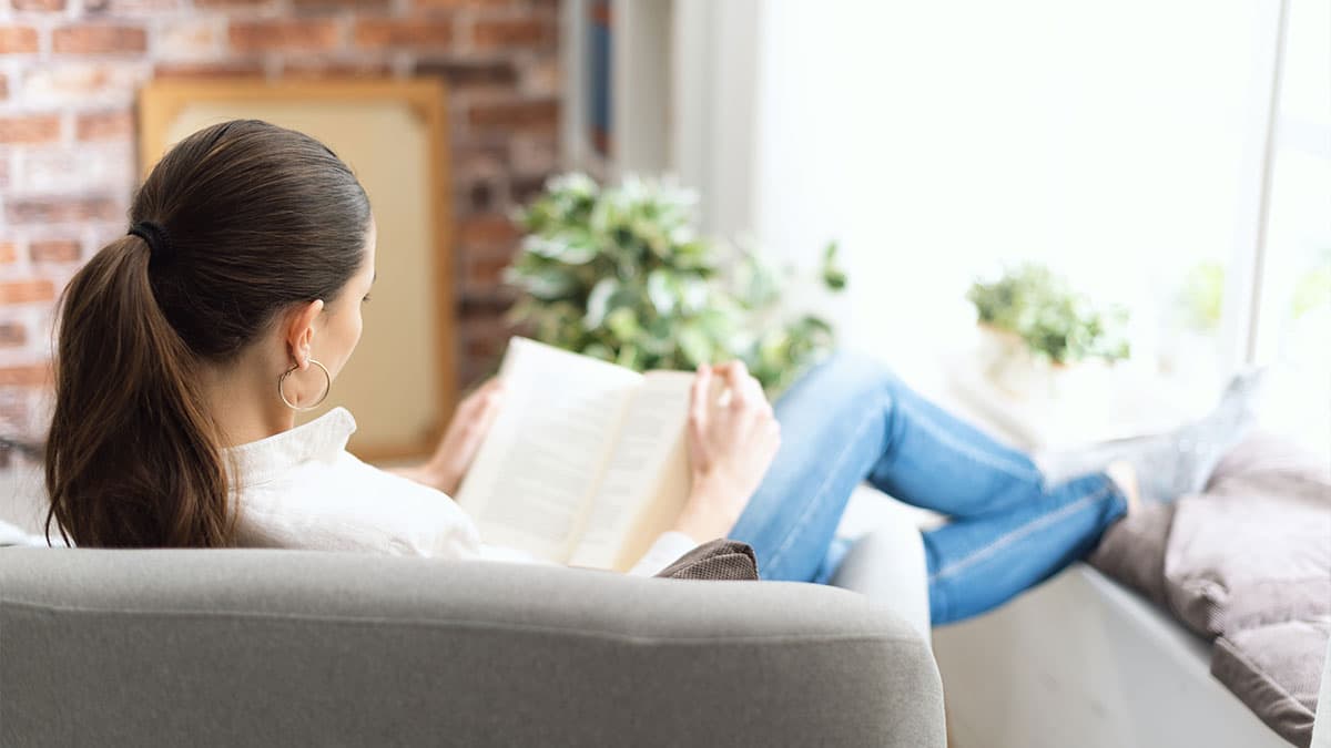Woman relaxing with a book while leaving time for rest after a wellness appointment